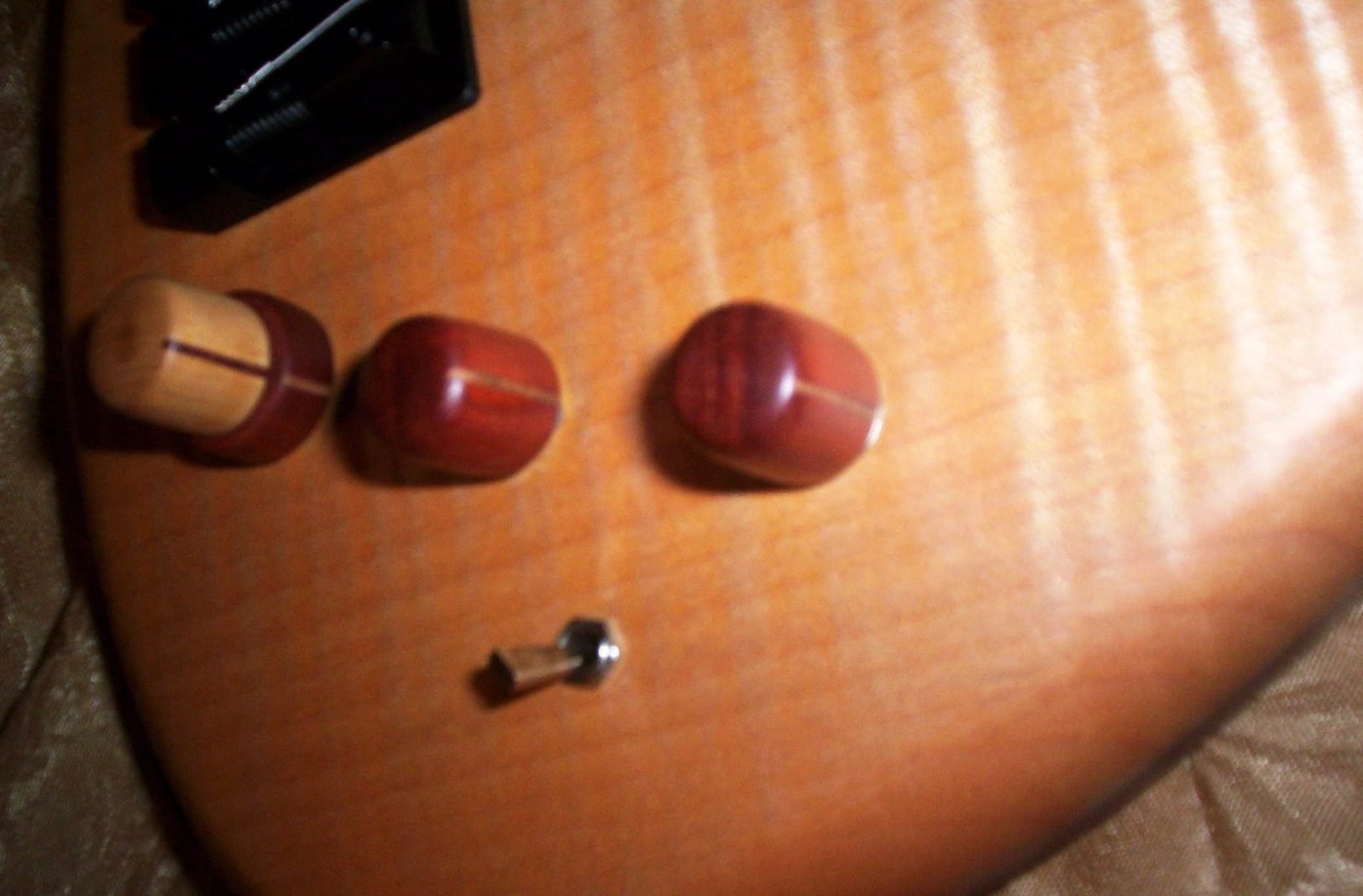 Hand-turned wooden control knobs installed on a flamed guitar top